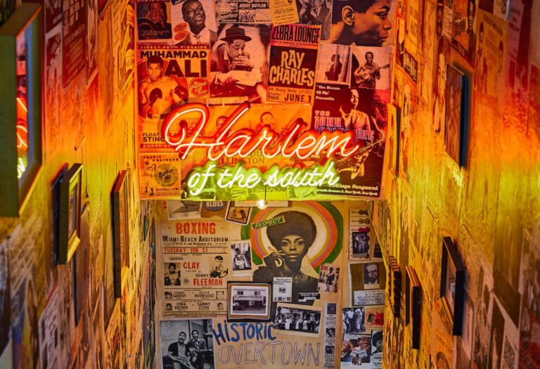 Interior of Red Rooster Overtown speakeasy with neon "Harlem of the South" sign and historic Overtown memorabilia